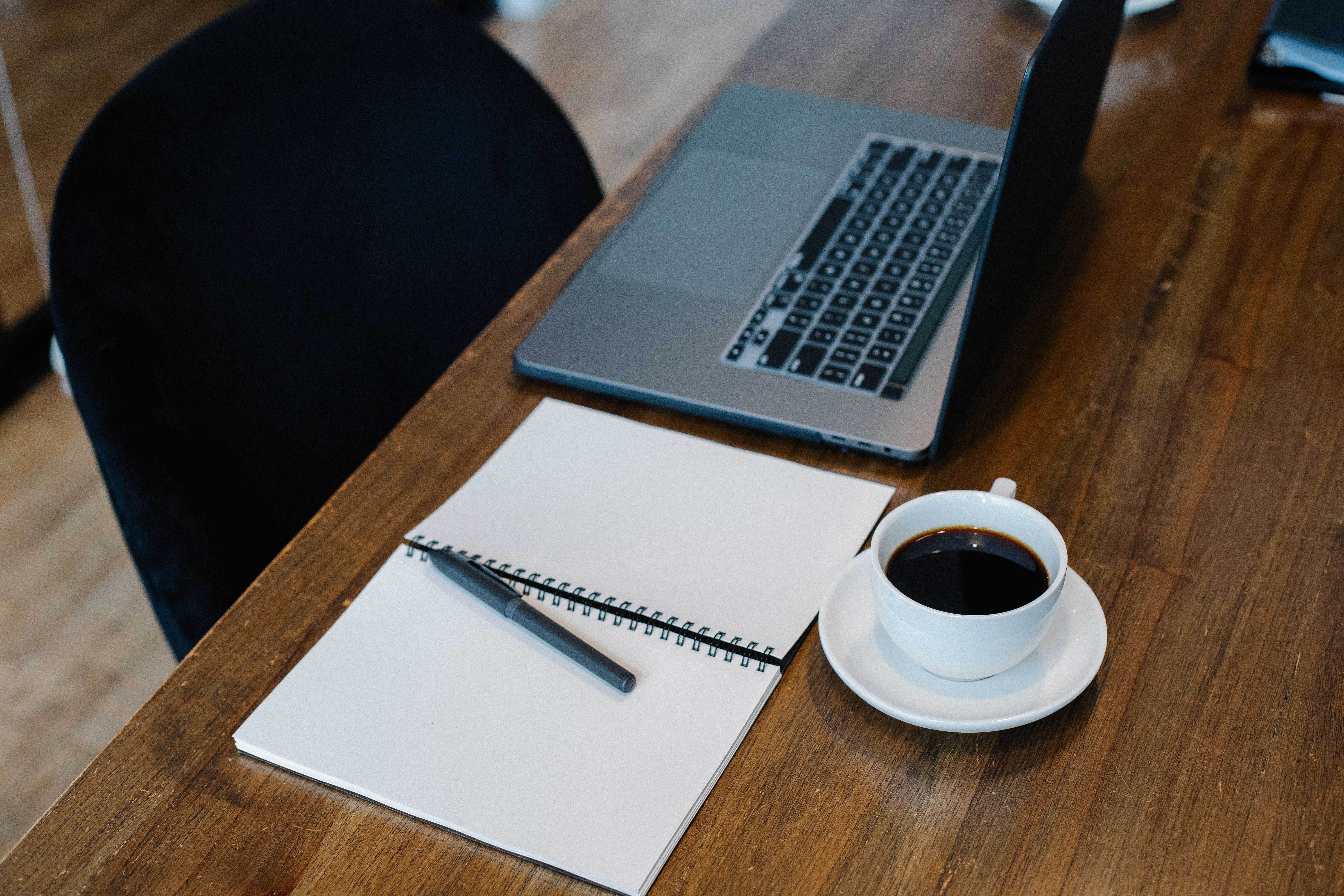 Blank notebook beside a laptop and coffee