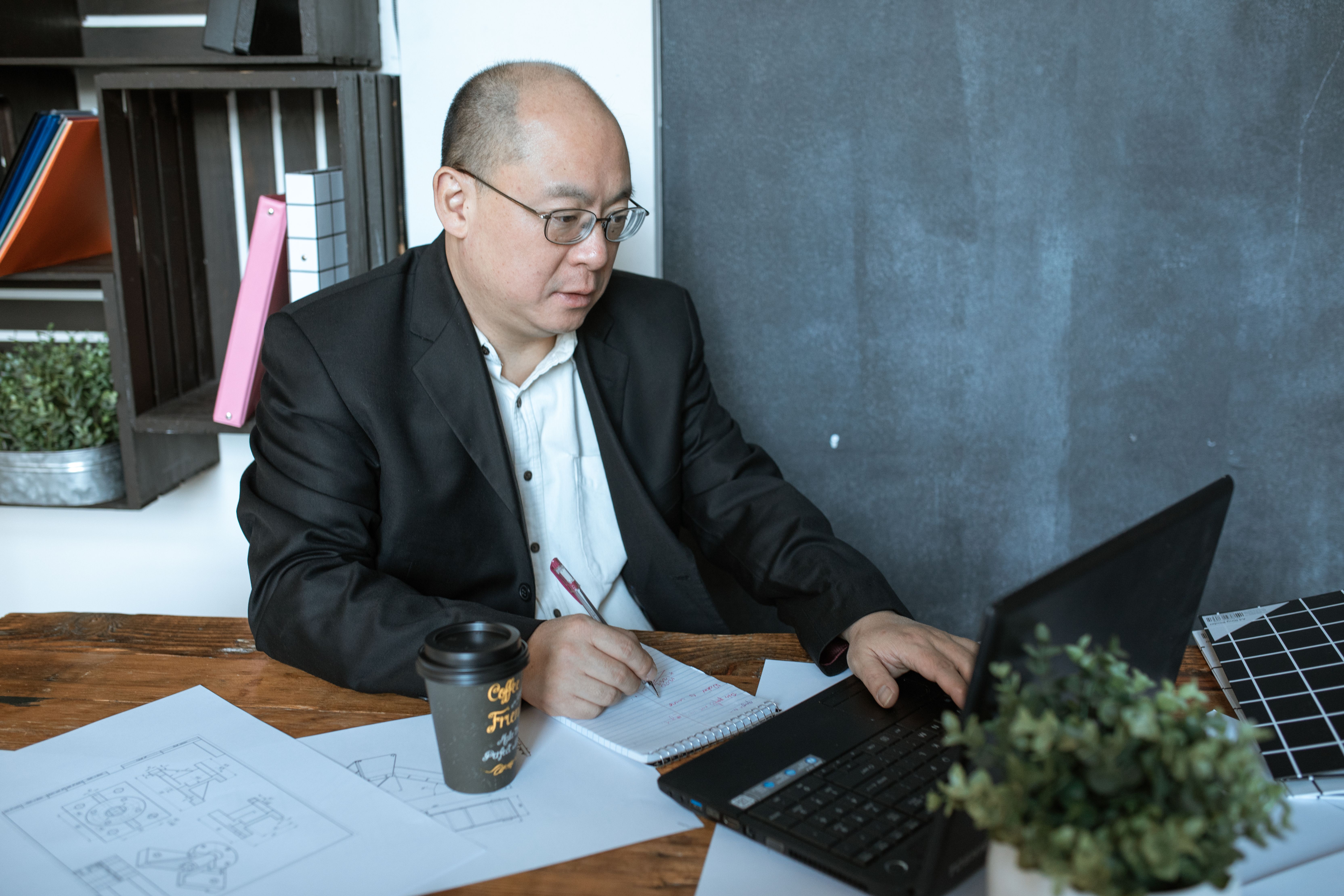 Business owner writing notes beside a laptop