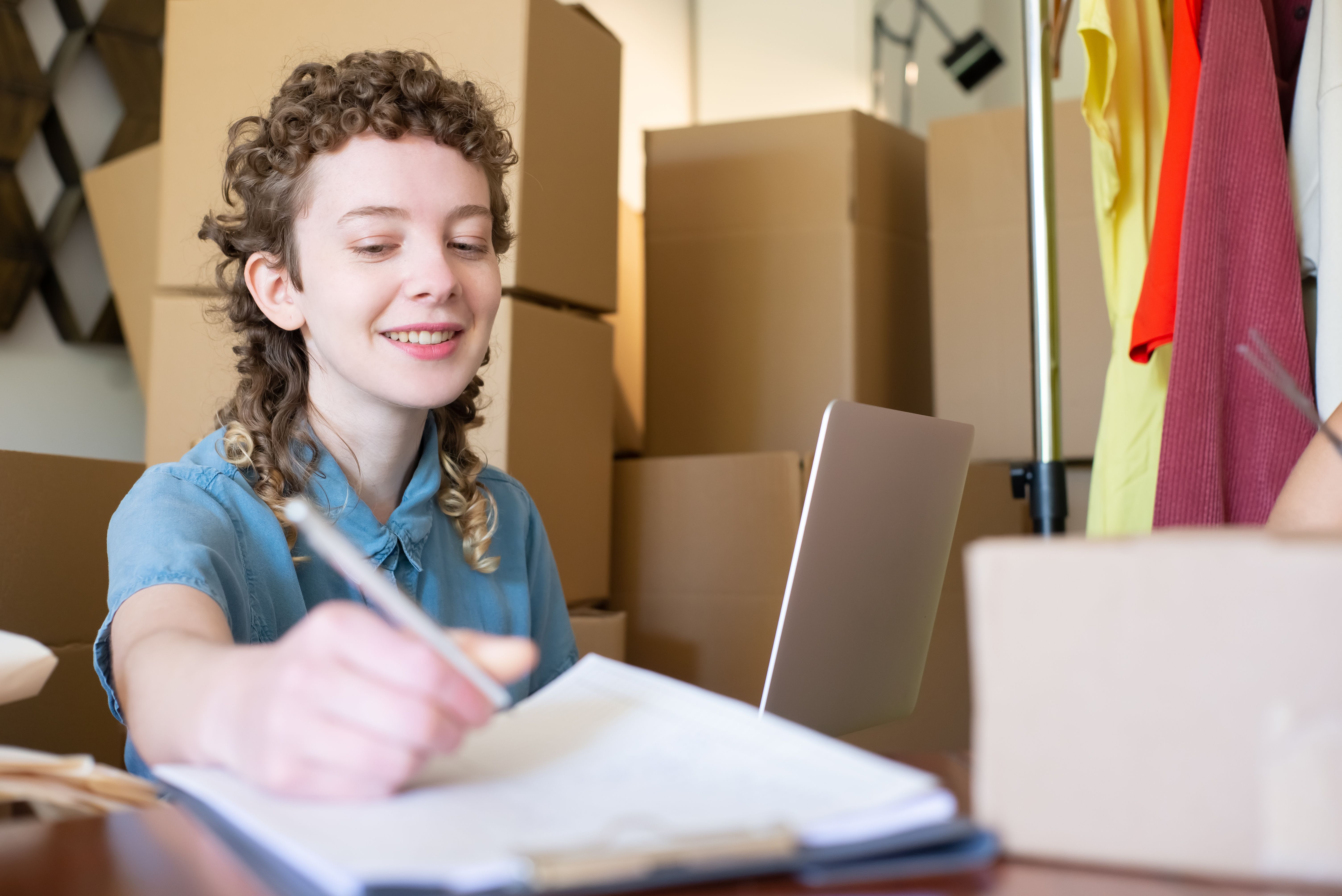 Small-business owner working on a laptop among shipping boxes